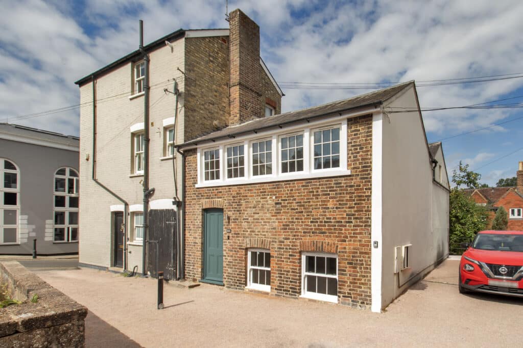 the outside of little mount sions, exposed brickwork front and a green door to standout