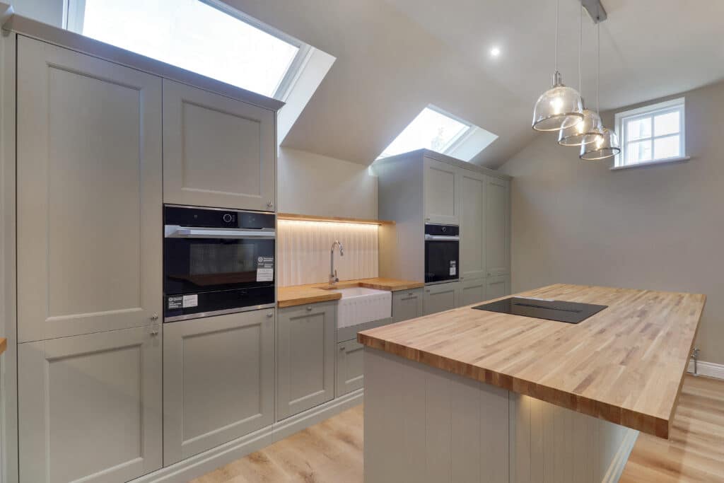 Sage green kitchen with island and wooden worktops